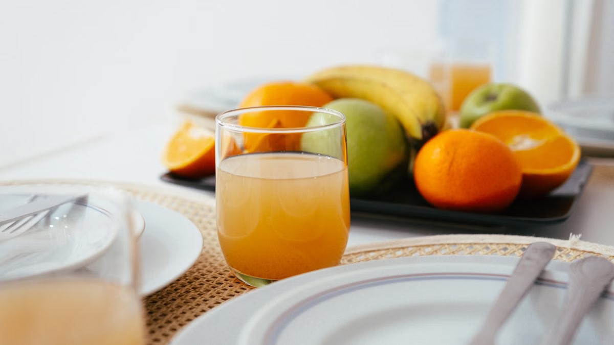 Bright and fresh breakfast setup featuring orange juice and a variety of fruits on a neatly arranged table.