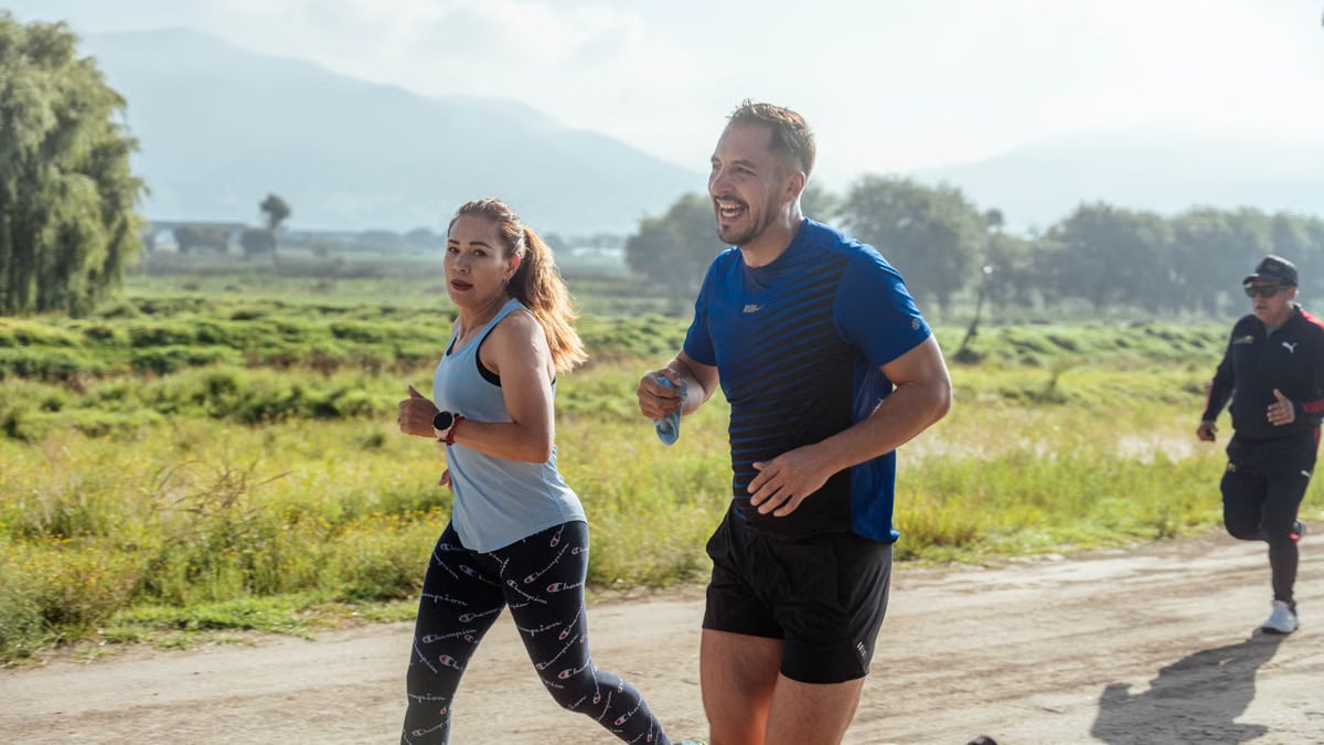 Two adults running on a rural dirt path, enjoying a sunny day outdoors.